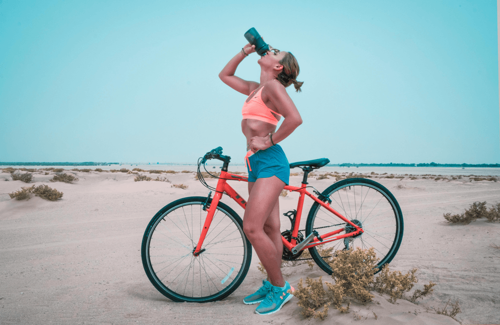 An athlete drinks water after a cycling workout in the heat – replacing fluids lost through sweat